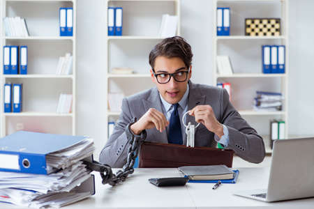 Busy employee chained to his office deskの写真素材