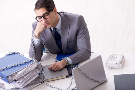 Busy employee chained to his office deskの写真素材
