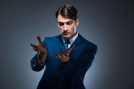 Businessman pressing virtual buttons on gray backgroundの写真素材