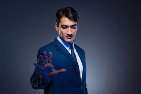 Businessman pressing virtual buttons on gray backgroundの写真素材