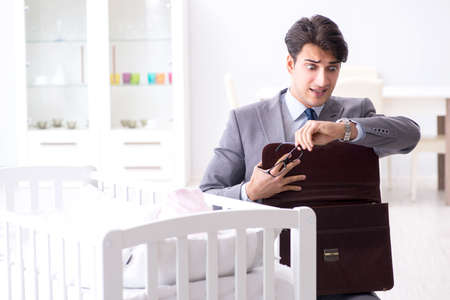 Young businessman trying to work from home caring after newbornの写真素材
