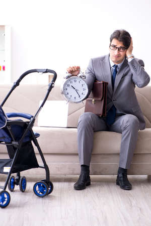 Businessman looking after newborn baby at home and teleworkingの写真素材
