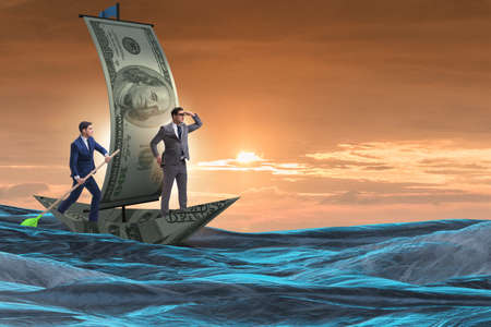 Business partnership with businessmen sailing on dollar boatの写真素材
