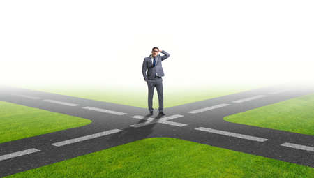 Young businessman at crossroads in uncertainty conceptの写真素材