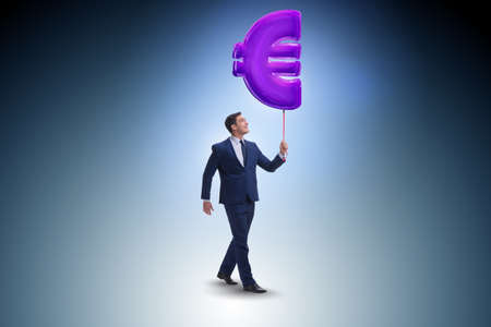 Businessman walking with inflatable euro signの写真素材