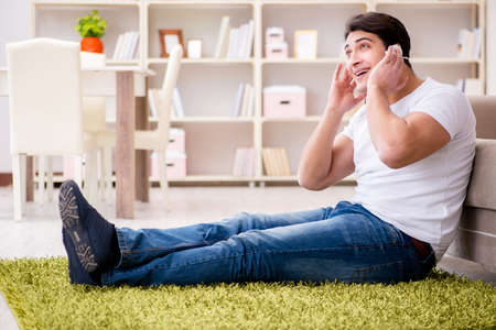 Young man student listening to music at homeの写真素材