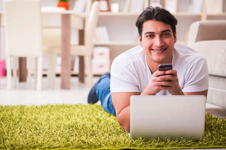 Man working on laptop at home on carpet floorの写真素材