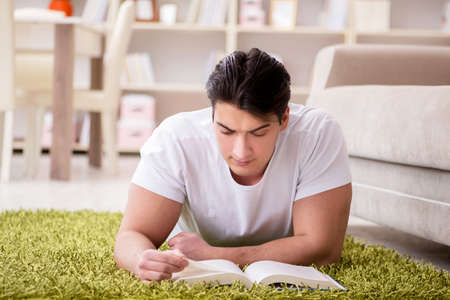Man reading book at home on floorの写真素材