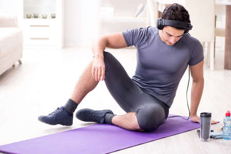 Man doing sports at home and listening to musicの写真素材