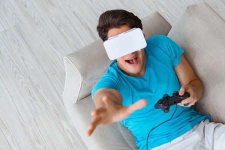 Young man wearing VR glasses relaxing on couch sofa