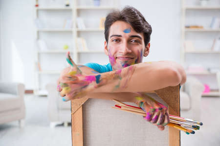 Young funny artist working on new painting in his studioの写真素材