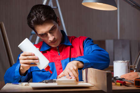 Young man gluing wood pieces together in DIY conceptの写真素材