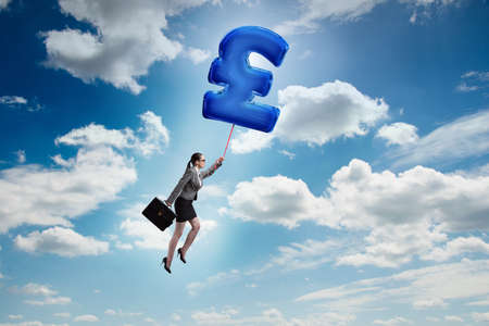 Businesswoman flying on british pound sign inflatable balloonの写真素材