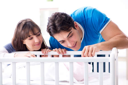 Happy young family at baby bed cotの写真素材