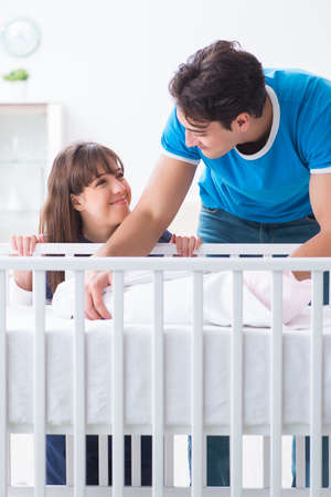Happy young family at baby bed cotの写真素材