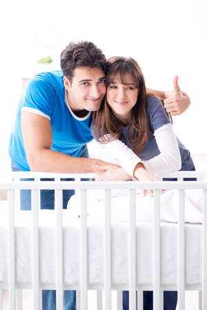Happy young family at baby bed cotの写真素材