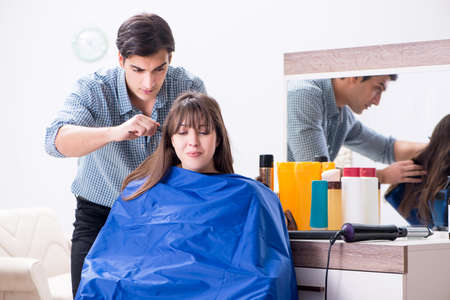 Male hairdresser doing haircut for woman customerの写真素材