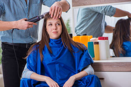 Male hairdresser doing haircut for woman customerの写真素材