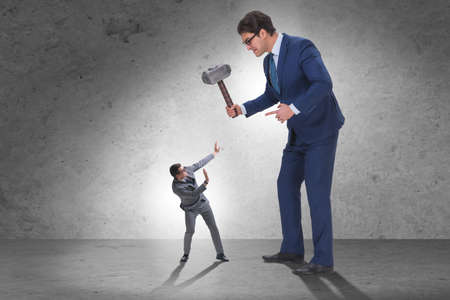 Bad angry boss threatening employee with hammerの写真素材