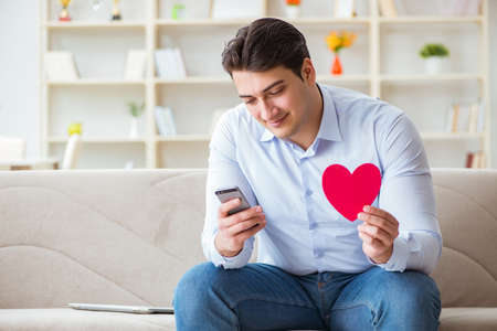 Young man chatting with his sweetheart over mobile phoneの写真素材