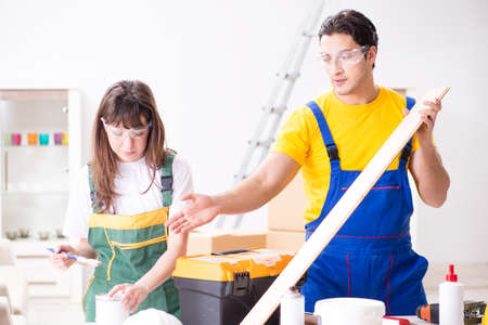 Man explaining woman woodworking tips in wood workshopの写真素材