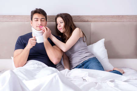 Loving wife taking care of injured husband in bedの写真素材