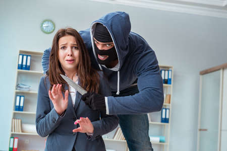 Criminal taking businesswoman as hostage in officeの写真素材