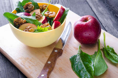 Spinach salad with nuts and apples served on tableの写真素材