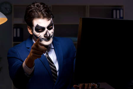 Businessman with scary face mask working late in office