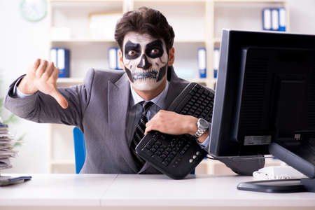 Businessman with scary face mask working in officeの写真素材