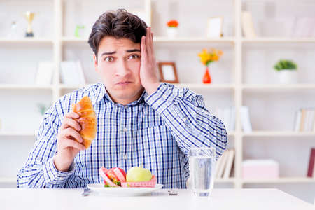 Man having dilemma between healthy food and bread in dieting concept