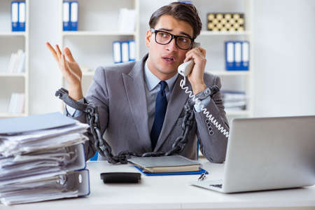 Busy employee chained to his office deskの写真素材