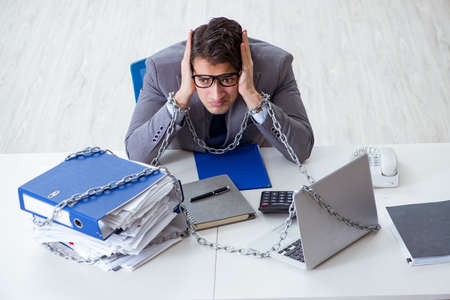 Busy employee chained to his office deskの写真素材