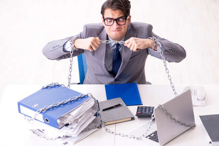 Busy employee chained to his office deskの写真素材