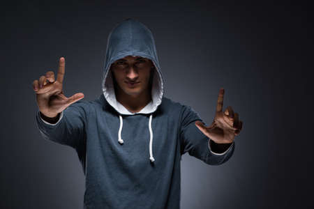 Young man wearing hoodie pressing virtual buttonsの写真素材