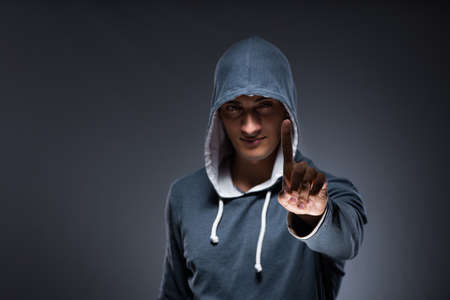 Young man wearing hoodie pressing virtual buttonsの写真素材