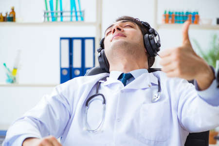 Happy excited doctor listening to music during lunch break in hospitalの写真素材