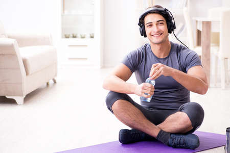 Man doing sports at home and listening to musicの写真素材