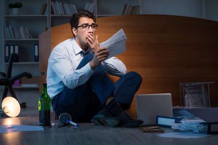 Stressed businessman working overtime in depressionの写真素材