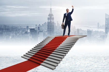 Young businessman climbing stairs and red carpetの写真素材