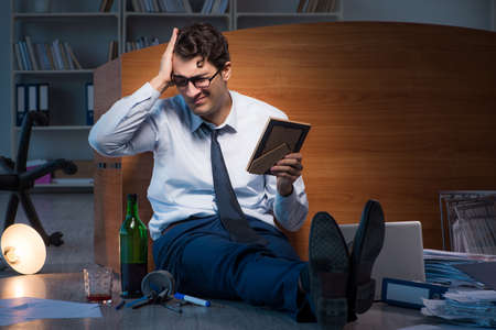 Sad employee in office missing his wife after divorce separationの写真素材