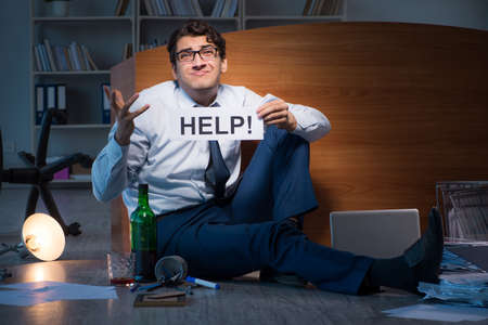 Employee asking for help and drinking under stress and despairの写真素材