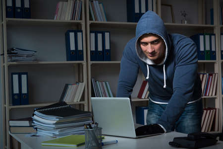 Young hacker hacking into computer at night