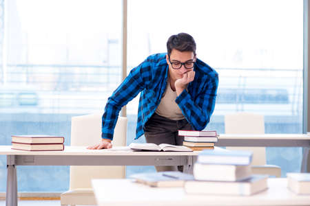 Student studying in the empty library with book preparing for examの写真素材