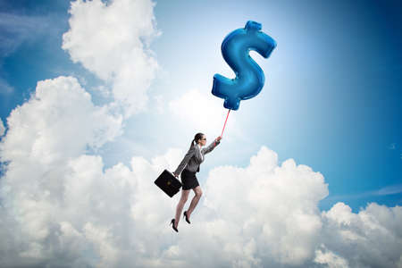 Businesswoman flying on dollar sign inflatable balloonの写真素材