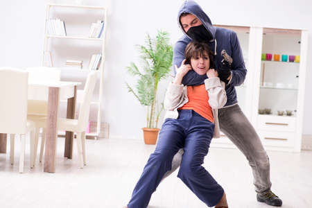 Armed man assaulting young woman at homeの写真素材