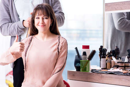 Man stylist working with woman in beauty salonの写真素材