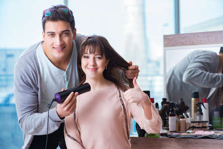 Man stylist working with woman in beauty salonの写真素材