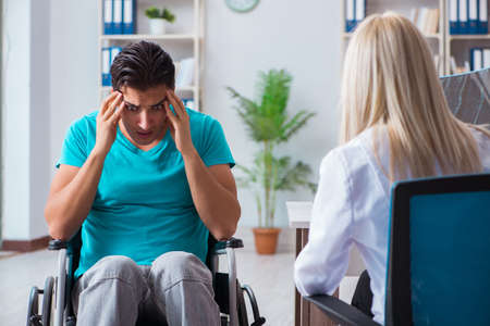 Disabled man in wheel chair visiting woman doctorの写真素材