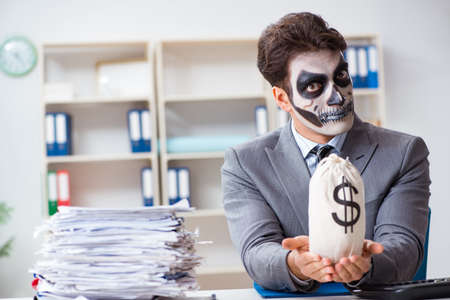 Businessmsn with scary face mask working in officeの写真素材